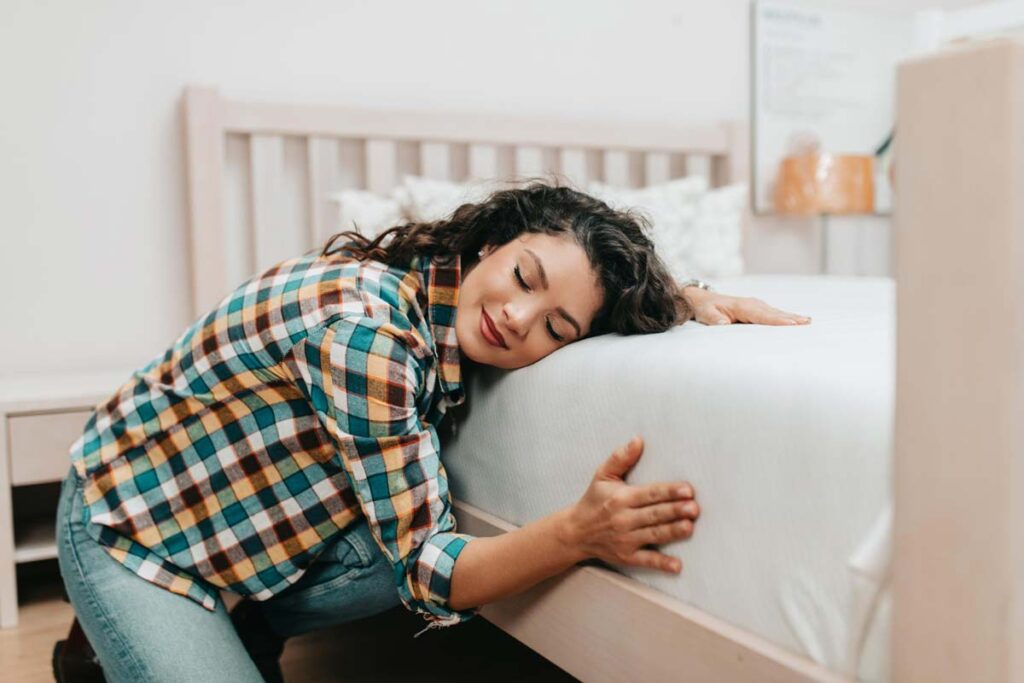 Młoda kobieta przytula się do materaca leżącego na łóżku